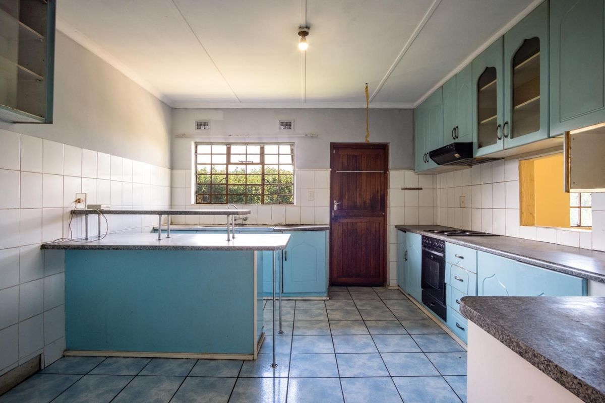A dated kitchen featuring blue cabinetry, laminate countertops, tiled flooring, and a built-in oven with extractor fan.