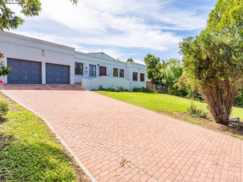 A well-maintained single-story residence featuring a paved driveway, double garage, and established garden, presenting a clean and inviting front facade.