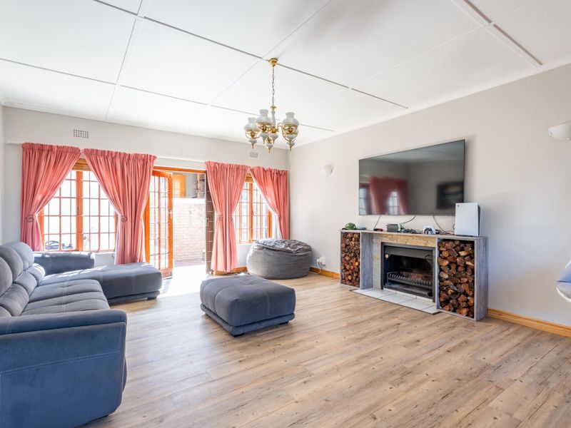 Spacious living room featuring a built-in fireplace with integrated wood storage, timber-look flooring, and direct access to the outdoor area through french doors.