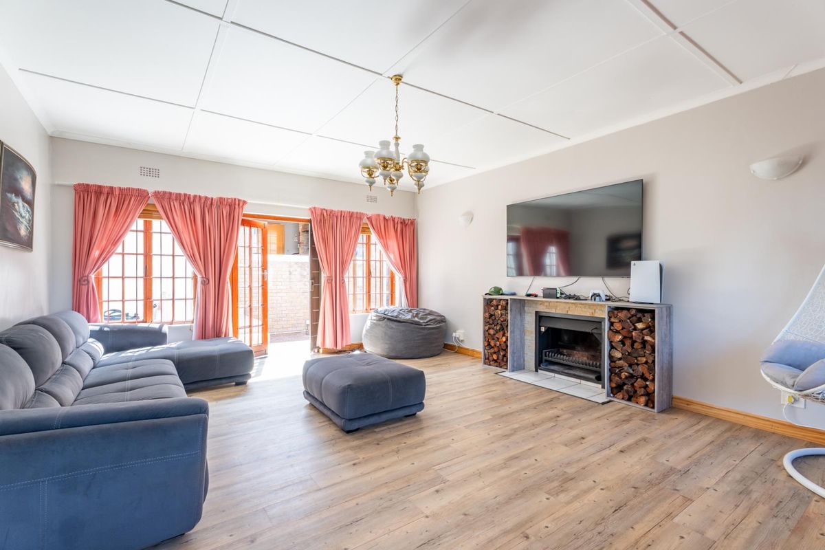 Spacious living room featuring a built-in fireplace with integrated wood storage, timber-look flooring, and direct access to the outdoor area through french doors.