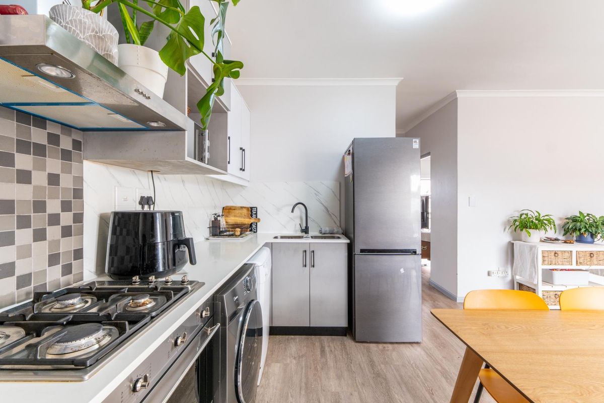 Modern kitchen featuring built-in gas hob, extractor fan, sleek cabinetry, and marble-look splashback, seamlessly integrated into an open-plan living area.