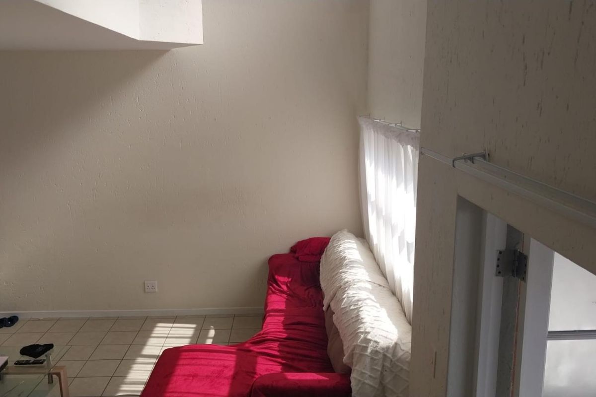 A living area featuring tiled flooring and natural light from a large window, providing a functional space for relaxation.