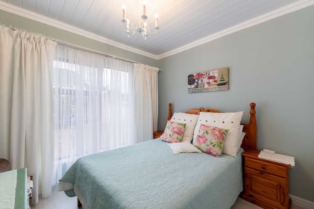A well-maintained bedroom featuring light blue walls, a white tongue-and-groove ceiling with crown molding, and large sliding glass doors providing natural light.