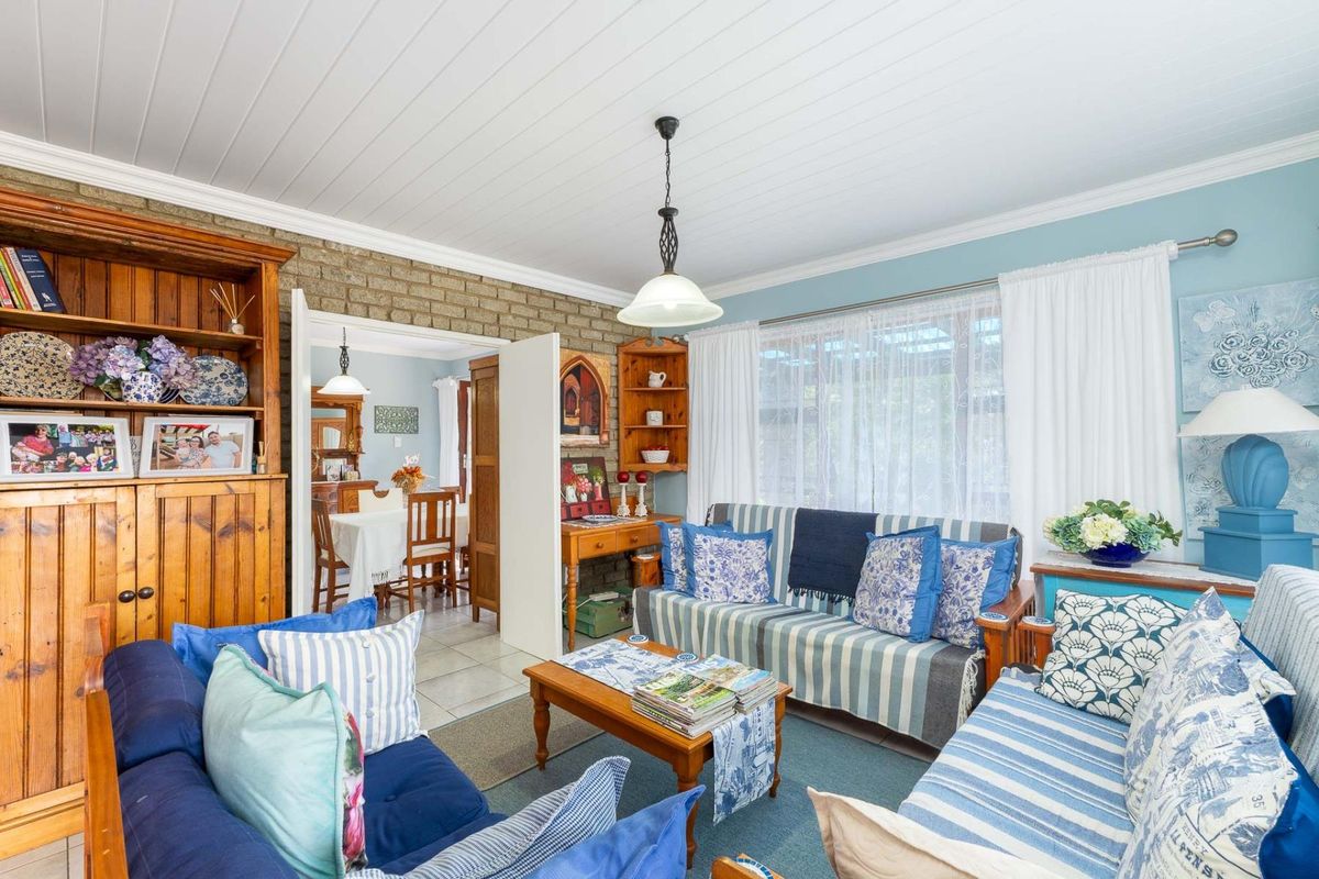 A cozy living room featuring a textured brick feature wall, tongue-and-groove ceiling, and direct access to the adjacent dining area.