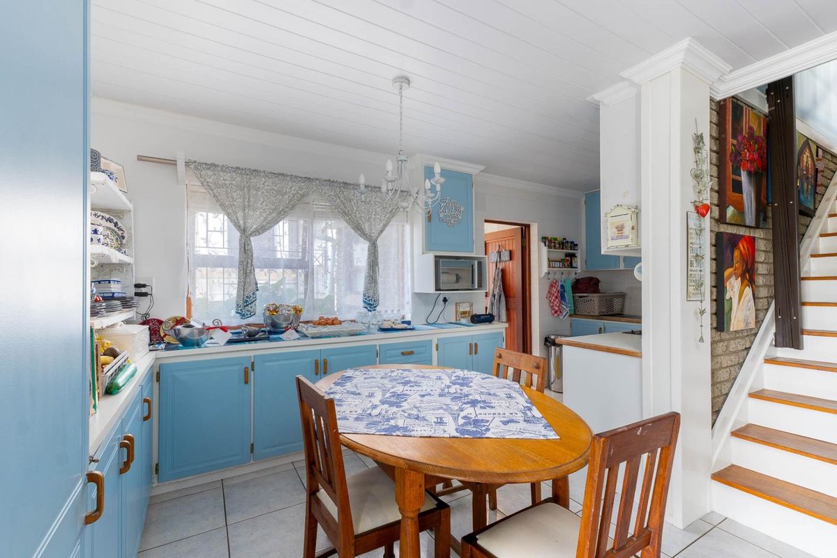 A functional kitchen featuring blue cabinetry, tiled flooring, and a built-in microwave, with an adjacent staircase leading to the upper level.