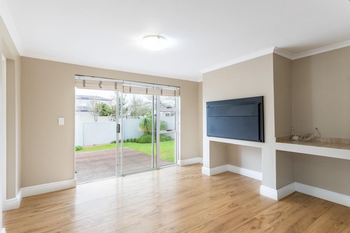 Bright living room featuring wood-look flooring, a built-in fireplace, and large sliding glass doors providing direct access to the rear patio and garden.