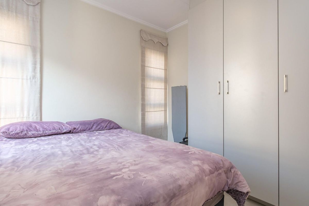 A functional bedroom featuring built-in floor-to-ceiling wardrobes and neutral wall finishes, providing ample storage space.