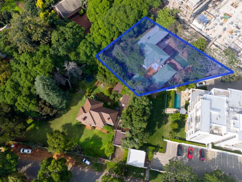 Aerial view of a residential property featuring mature trees, established garden areas, and existing building structures within a suburban setting.