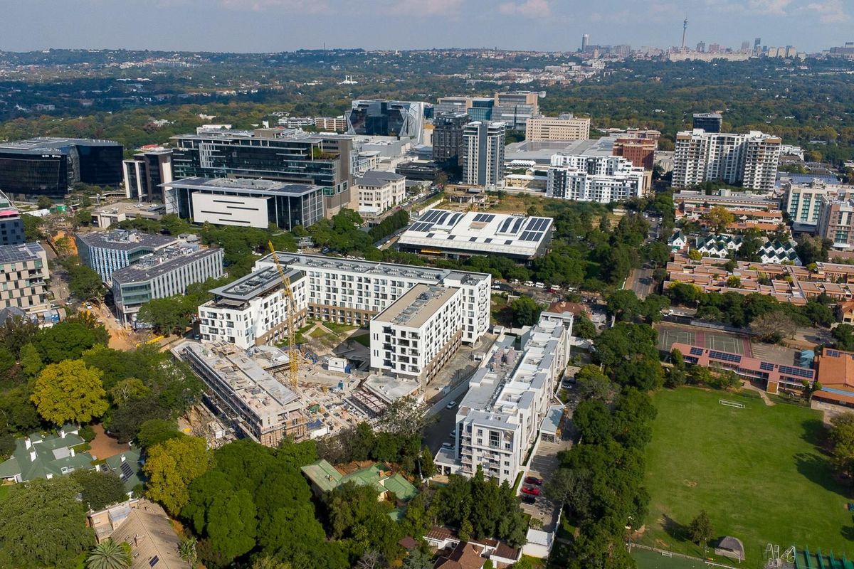 An aerial view of a dense urban landscape featuring a mix of modern residential apartment complexes, commercial office buildings, and an active construction site.