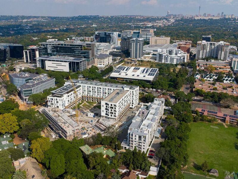 An aerial view of a dense urban landscape featuring a mix of modern residential apartment complexes, commercial office buildings, and an active construction site.