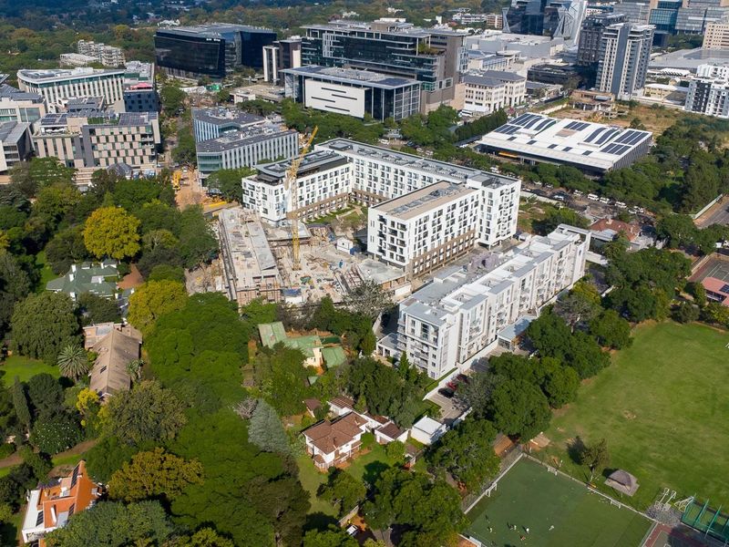 Aerial view of a residential development site situated within an established urban neighborhood with surrounding greenery and commercial buildings.