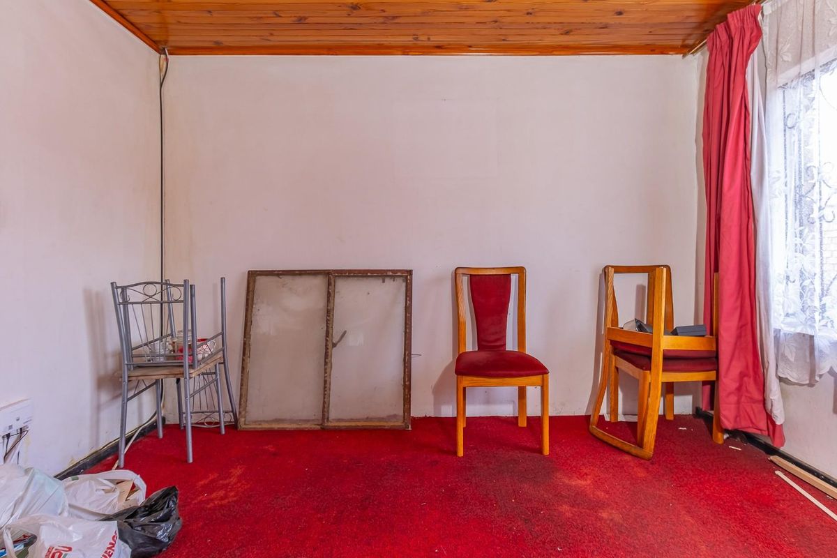 A bedroom featuring a timber ceiling, red carpeting, and a window with security bars, requiring cosmetic updates to modernize the space.