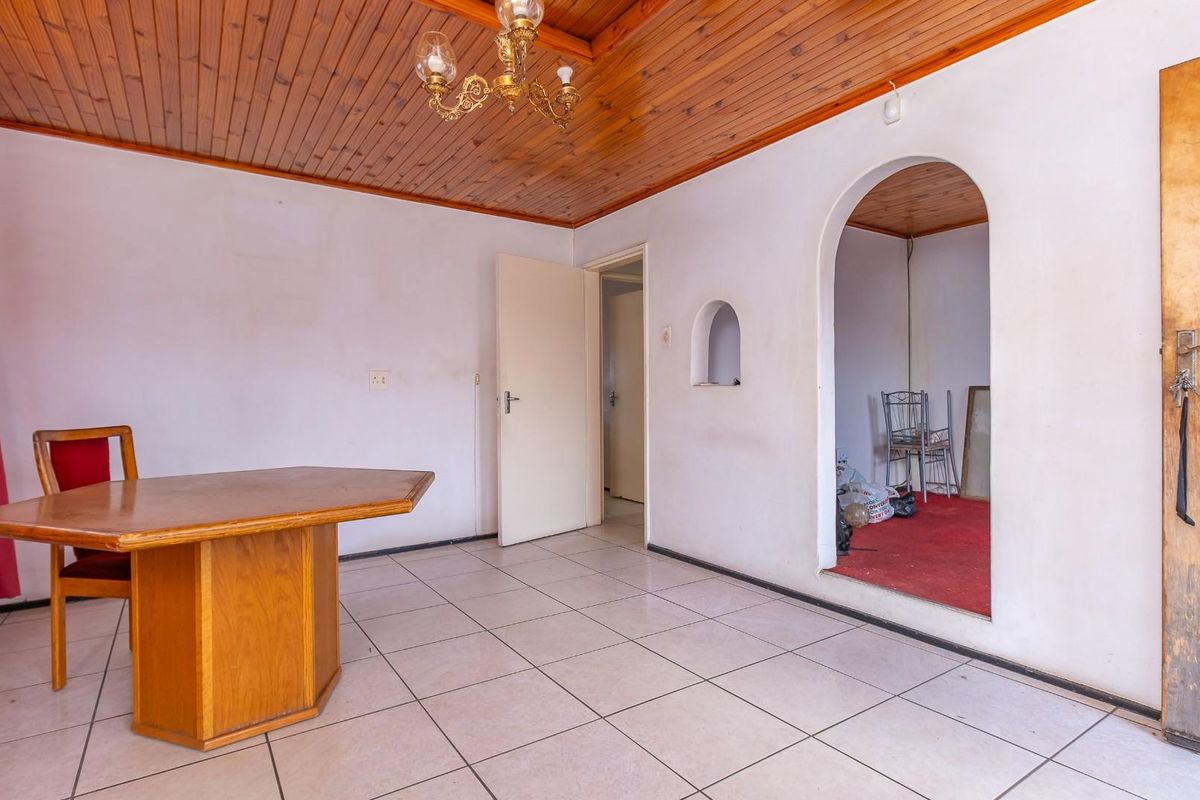 A living area featuring tiled flooring, a timber-clad ceiling, and an arched entryway leading to an adjacent room.