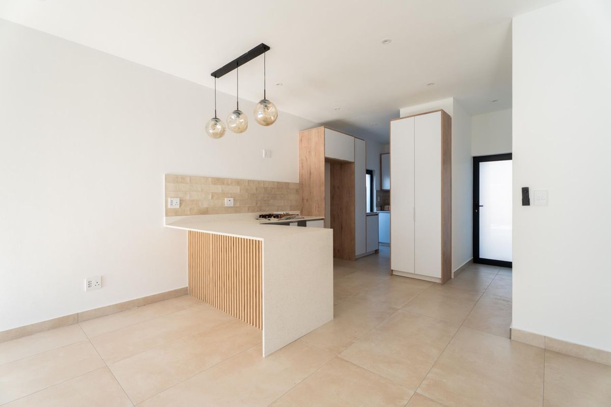 Modern kitchen featuring clean lines, stone countertops, built-in cabinetry, and a tiled backsplash, offering a bright and functional culinary space.