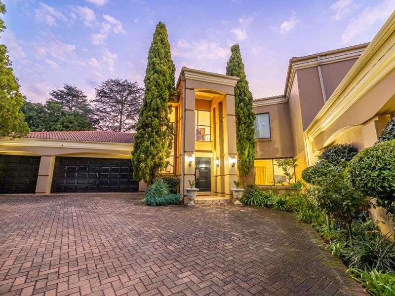 A grand double-storey front facade featuring a paved driveway, integrated double garage, and a prominent entrance portico with established landscaping.