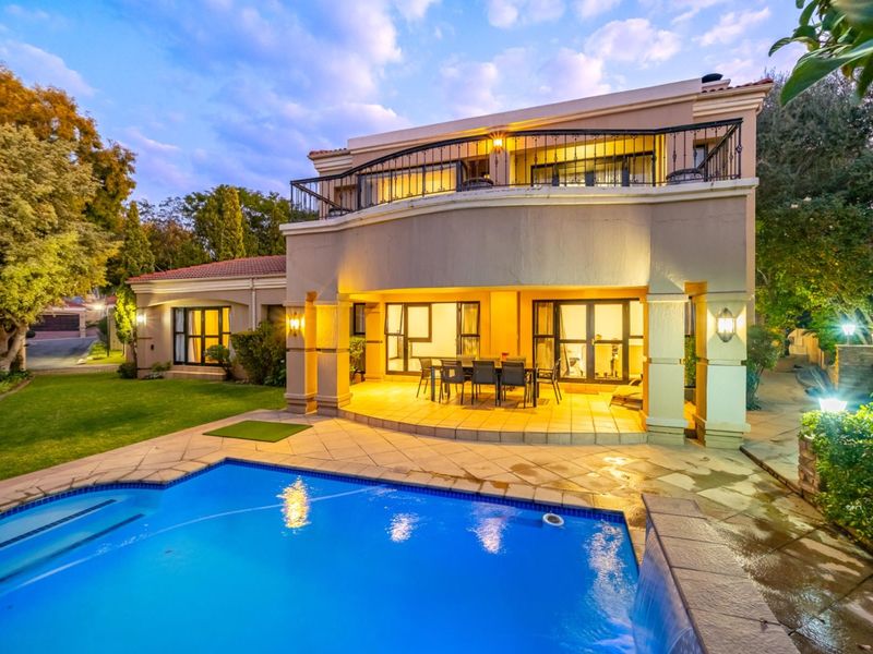 A spacious rear exterior view featuring a swimming pool, a covered patio area, and a balcony on the upper level of the residence.