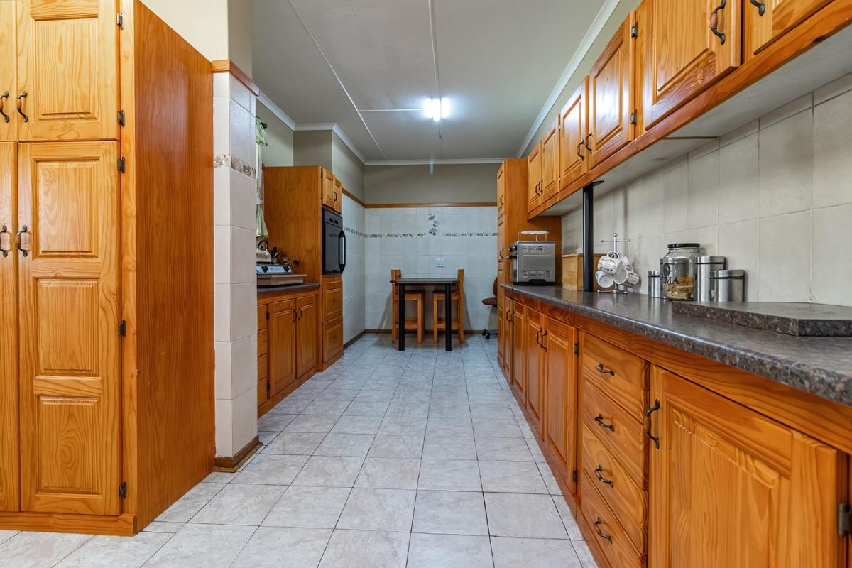 A functional kitchen featuring extensive wooden cabinetry, tiled flooring, and tiled splashbacks, offering a traditional layout with ample storage space.
