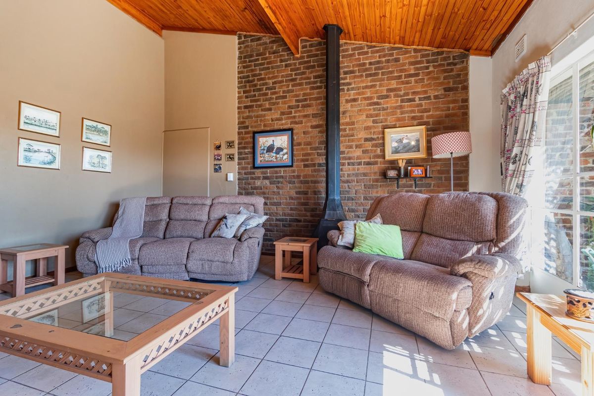 A living room featuring a vaulted timber-clad ceiling, a prominent exposed brick feature wall, and a built-in fireplace flue.