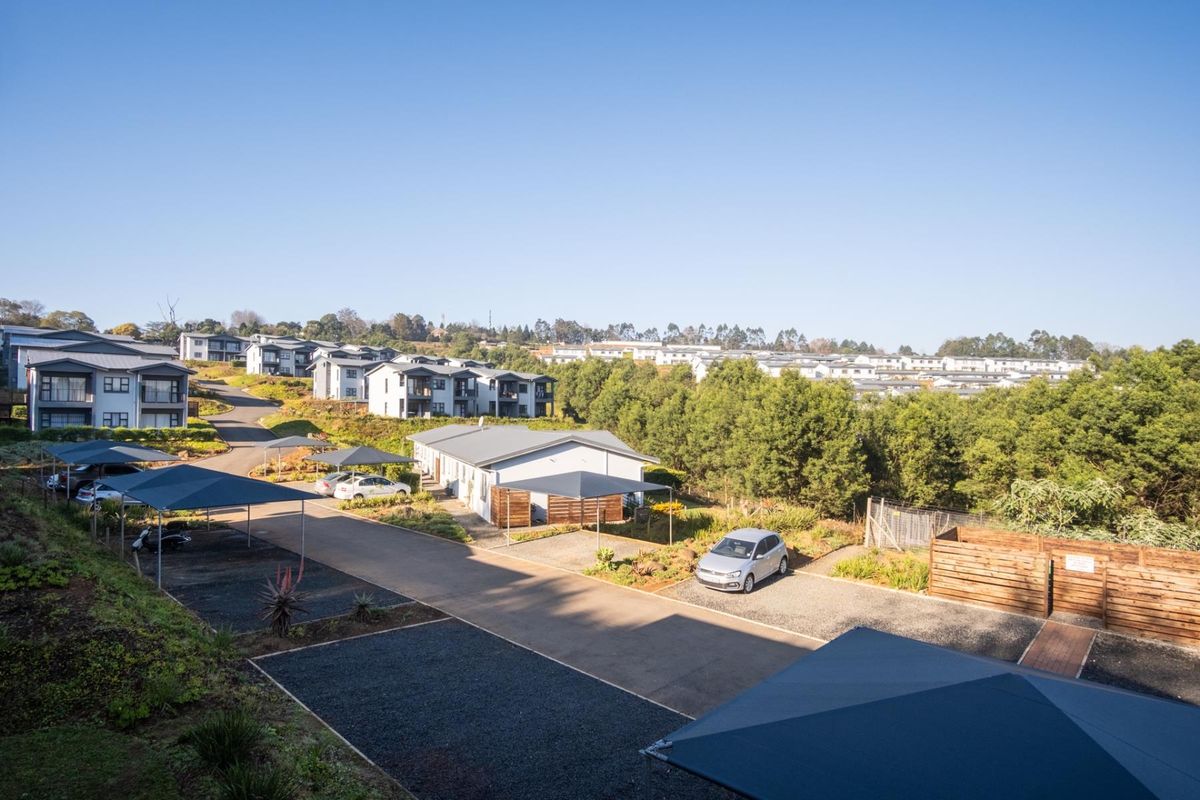 An elevated view of the apartment complex grounds, featuring paved driveways, covered parking bays, and landscaped surroundings.