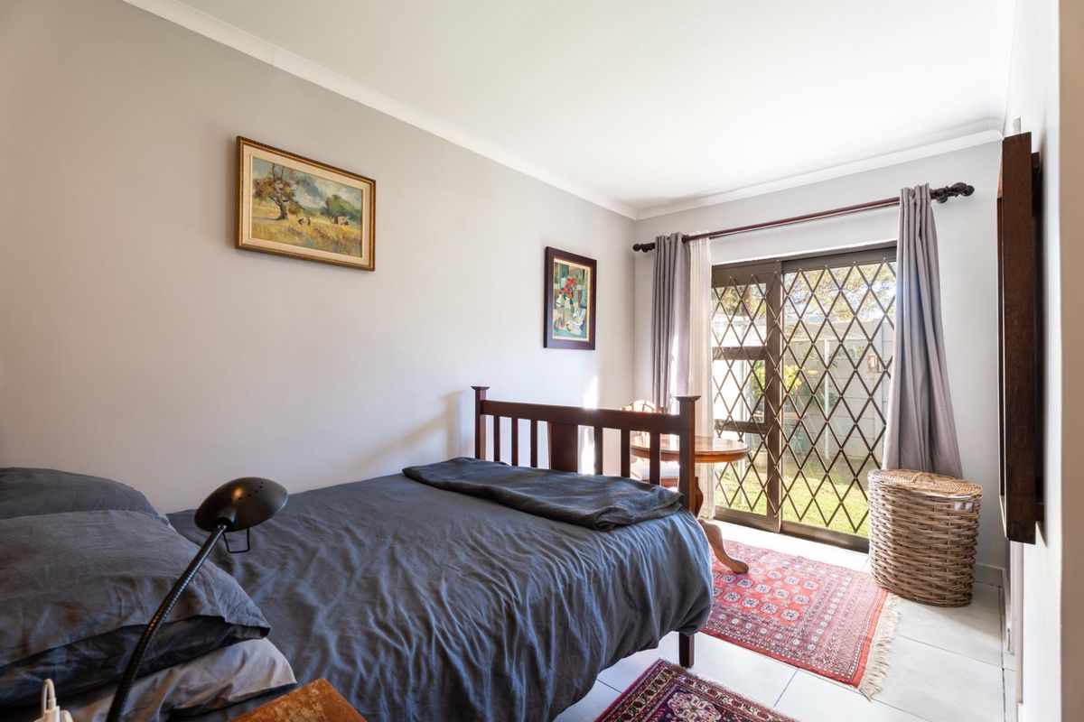 A bedroom featuring tiled flooring and a sliding glass door with a security gate, providing direct access to the outdoor area.