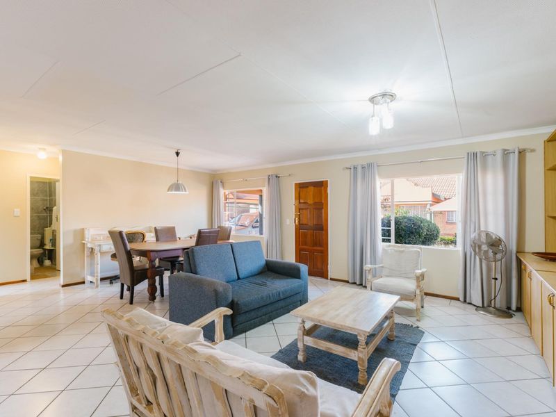 Spacious open-plan living and dining area featuring tiled flooring, built-in cabinetry, and direct access to the exterior.