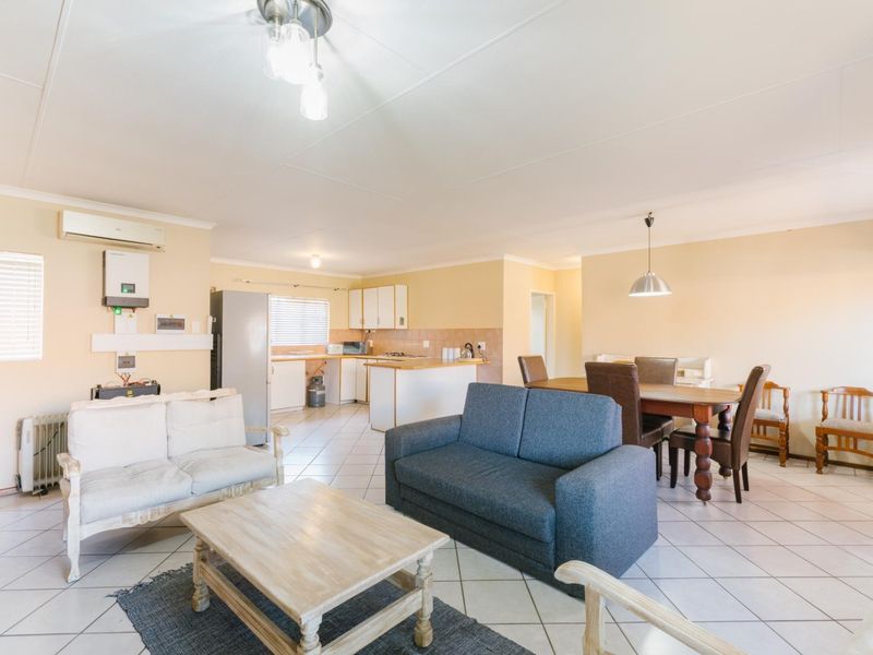 Spacious open-plan living, dining, and kitchen area featuring tiled flooring, neutral walls, and integrated inverter system for energy efficiency.
