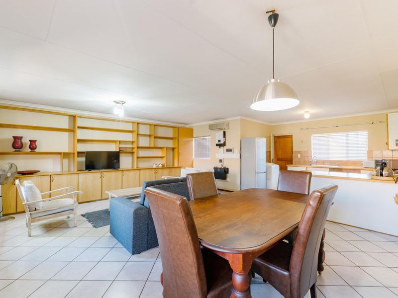 Spacious open-plan living and dining area featuring tiled floors, extensive built-in cabinetry, and a functional kitchen layout with ample storage.