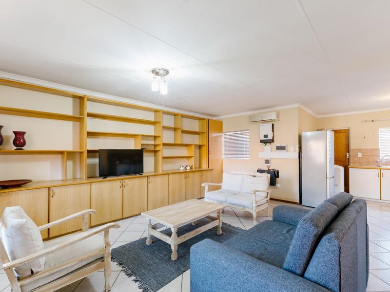 Open-plan living area featuring tiled floors, extensive built-in cabinetry, and an integrated kitchen space with neutral finishes.