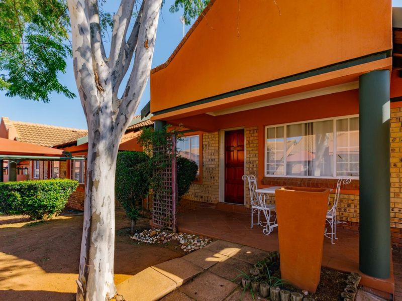 A covered patio area featuring tiled flooring and brick exterior walls, providing a functional outdoor space for relaxation.
