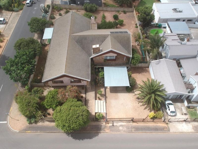 Aerial view of a residential property featuring a tiled roof, solar panels, a carport, and a spacious garden area.