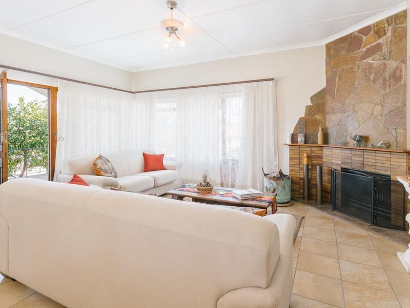 Spacious living room featuring a prominent stone fireplace, tiled flooring, and direct access to an outdoor area through a glass door.