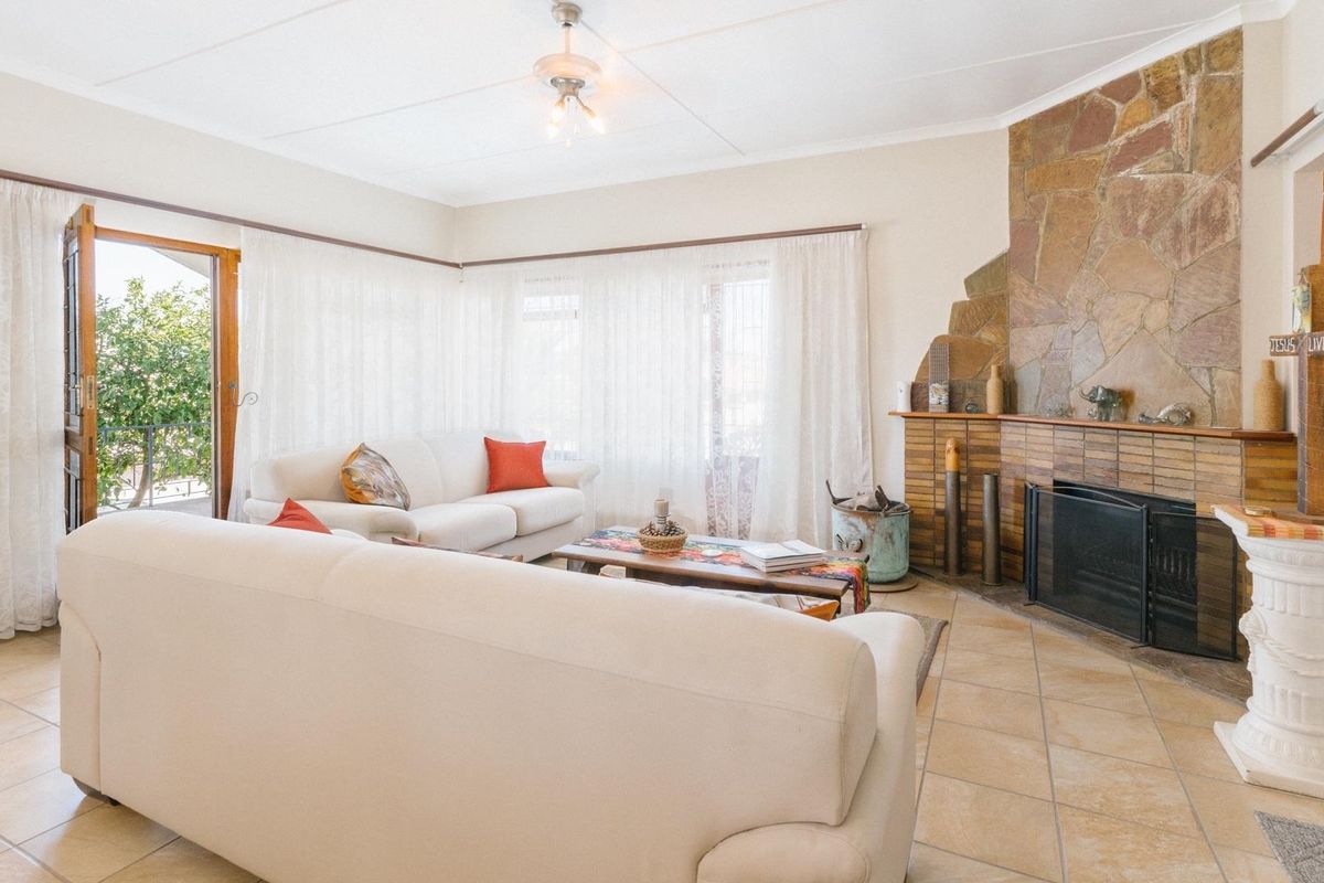 Spacious living room featuring a prominent stone fireplace, tiled flooring, and direct access to an outdoor area through a glass door.