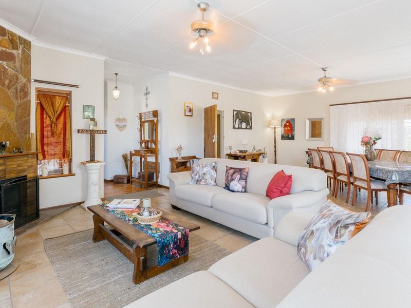 Spacious open-plan living and dining area featuring a prominent stone fireplace, tiled flooring, and ceiling fans, offering a comfortable and functional layout.