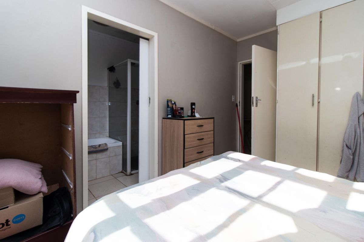 Bedroom featuring built-in cupboards and an attached en-suite bathroom with a shower and bathtub combination.