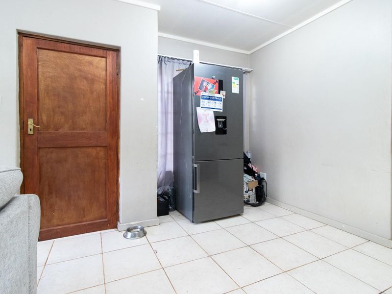 A functional kitchen area featuring tiled flooring and a solid wooden door, providing a neutral base for potential updates or renovation.