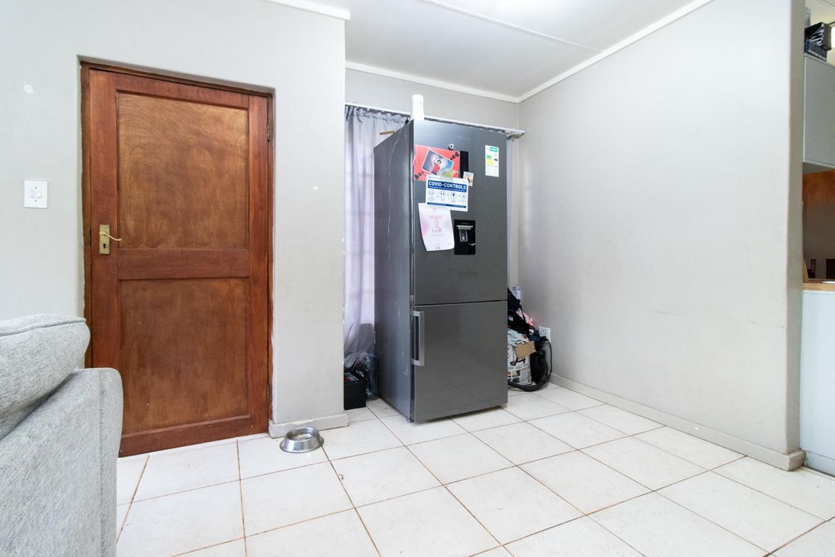 A functional kitchen area featuring tiled flooring and a solid wooden door, providing a neutral base for potential updates or renovation.
