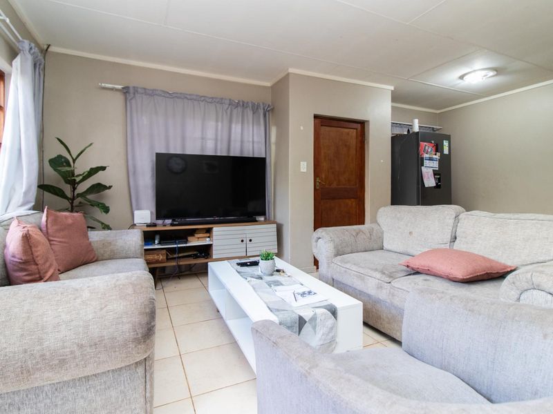 A functional living room featuring tiled flooring and a classic timber door, providing a comfortable and practical space for relaxation.