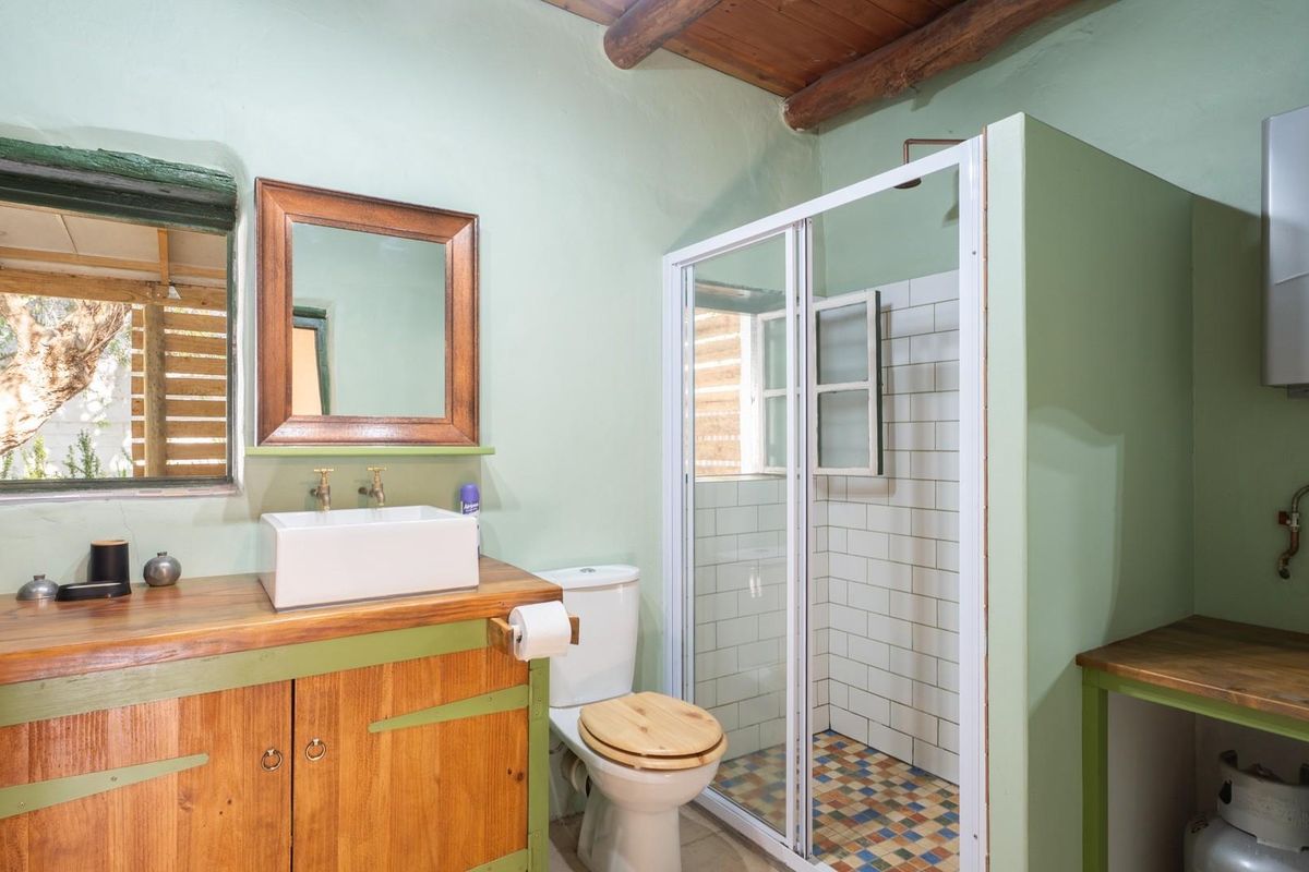 A rustic-style bathroom featuring a timber vanity with a vessel sink, a tiled shower enclosure, and an exposed gas water heater.