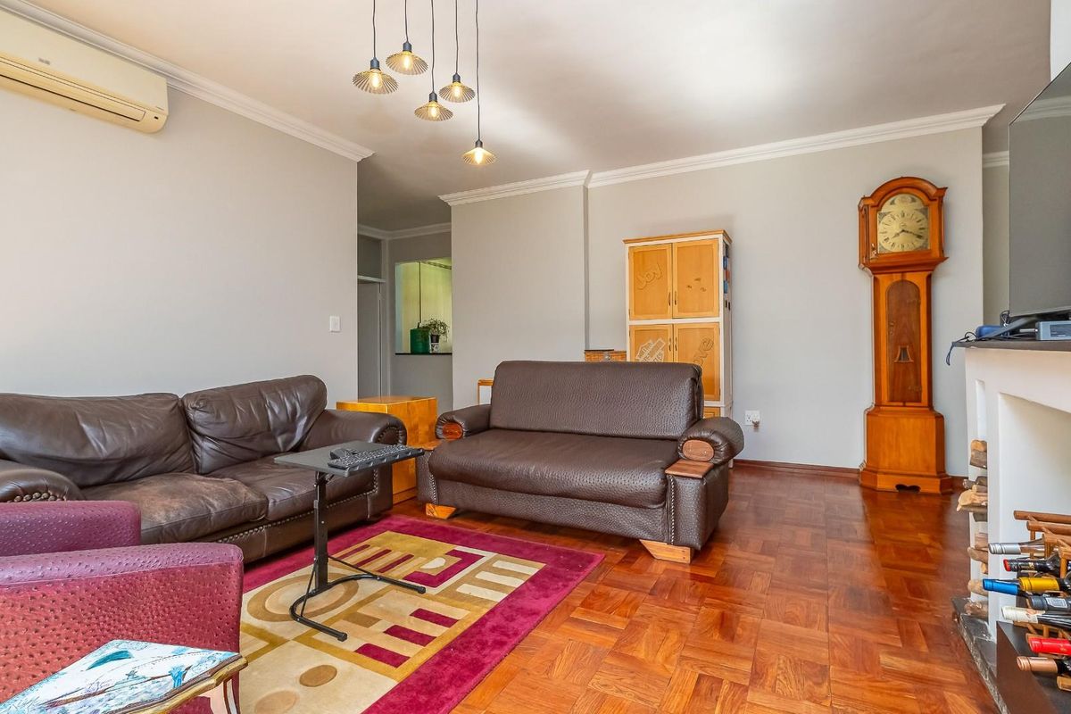 A living room featuring parquet flooring, crown molding, and a wall-mounted air conditioning unit.