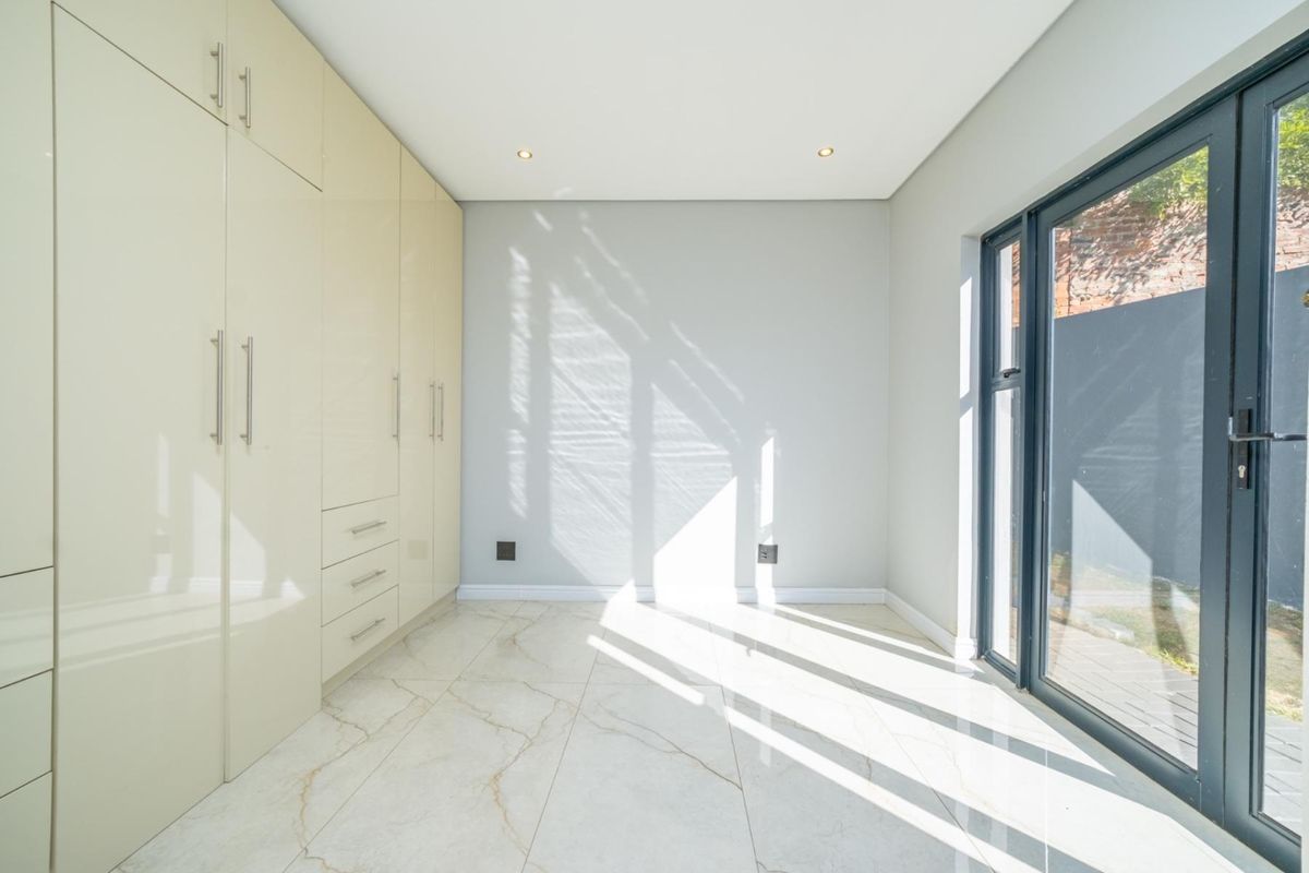 A bright, modern room featuring high-gloss built-in cabinetry, marble-look tiled flooring, and large glass sliding doors providing direct access to the exterior.