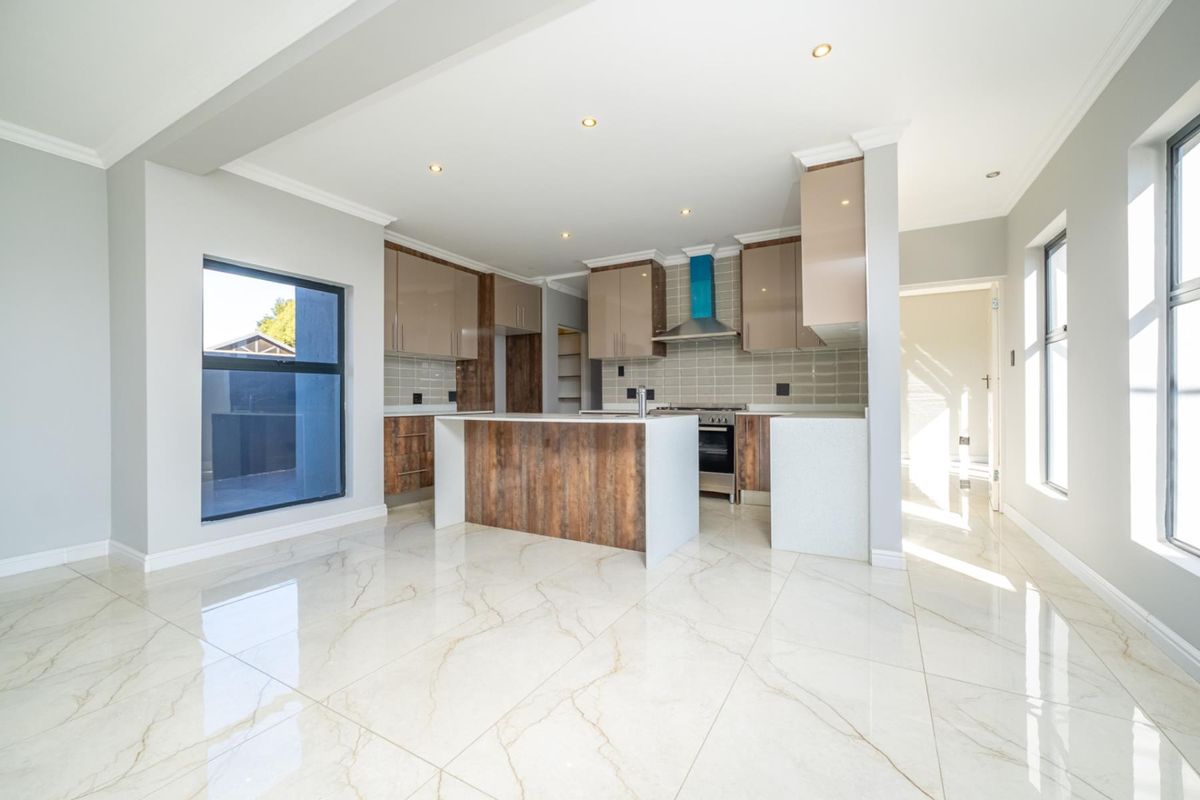 Modern kitchen featuring high-gloss cabinetry, a central island with stone countertops, integrated stove and extractor fan, and polished marble-look floor tiles.