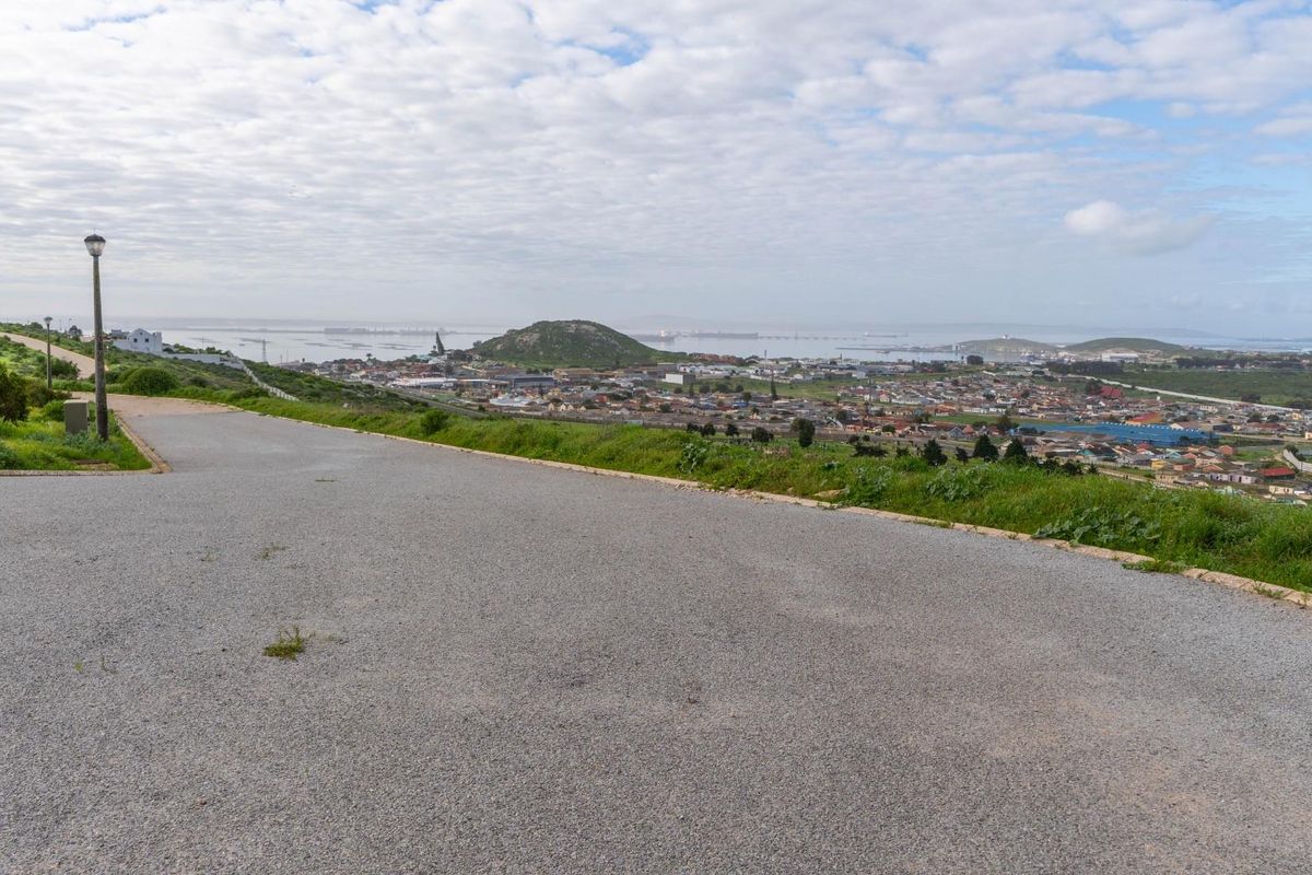 A scenic view overlooking the surrounding residential area and coastline from an elevated position on a paved road.