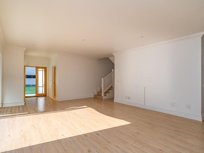 Spacious, light-filled living area featuring modern laminate flooring, a built-in wine rack, and direct access to the garden through sliding glass doors.