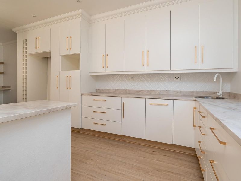 Modern kitchen featuring white cabinetry, marble-look countertops, herringbone tile backsplash, and wood-look flooring in a clean, minimalist design.