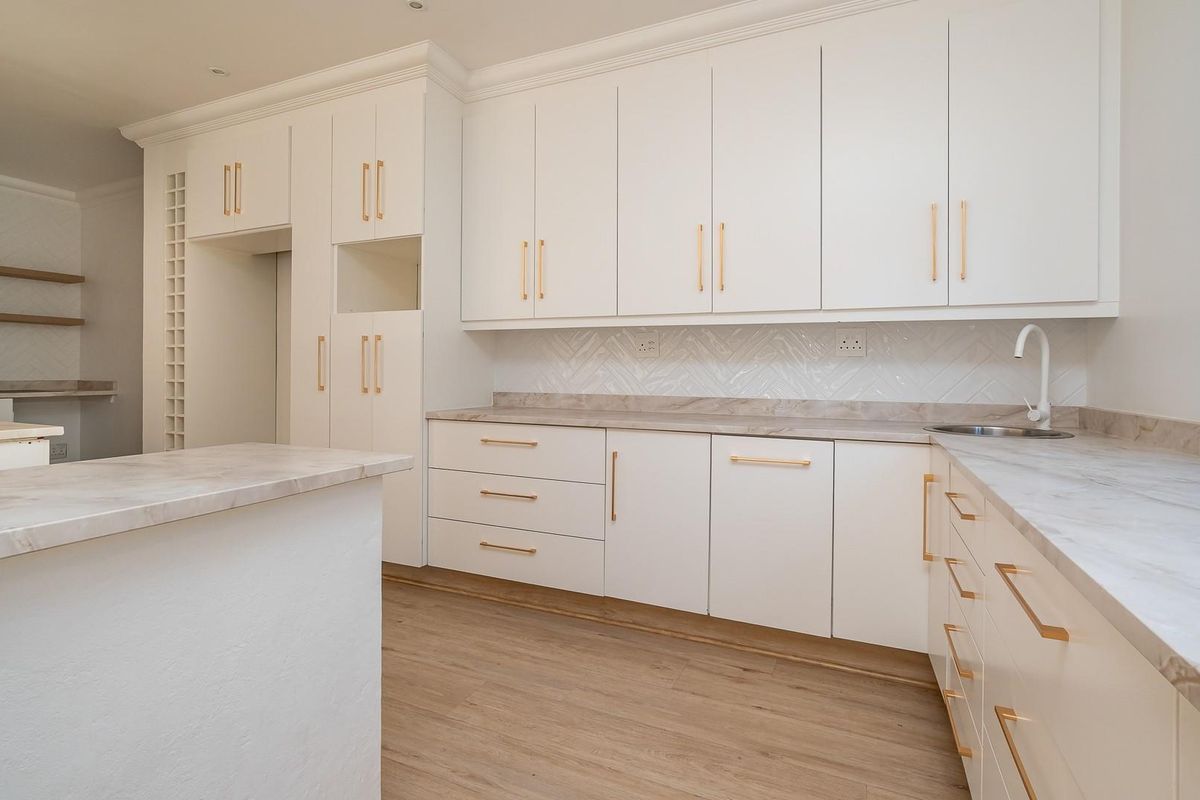 Modern kitchen featuring white cabinetry, marble-look countertops, herringbone tile backsplash, and wood-look flooring in a clean, minimalist design.