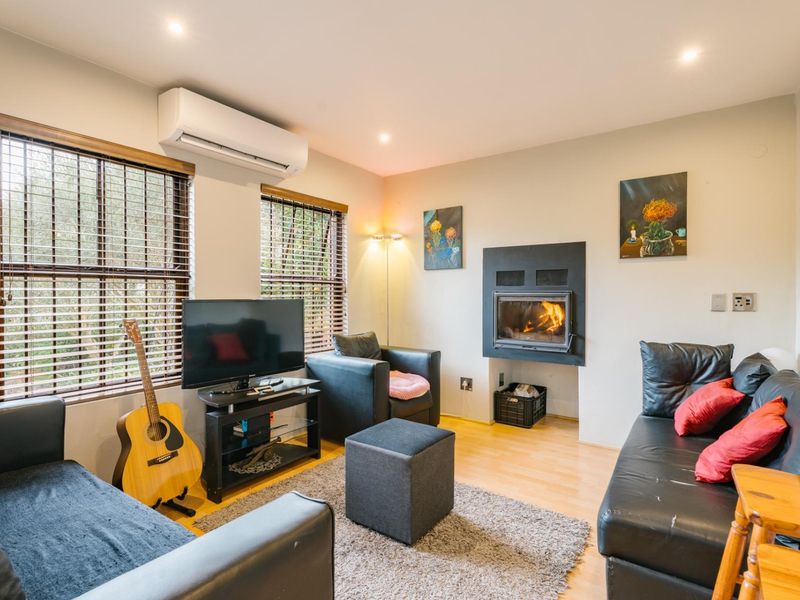 A cozy living room featuring a built-in fireplace, split-system air conditioning, and laminate flooring, offering a comfortable and functional space.