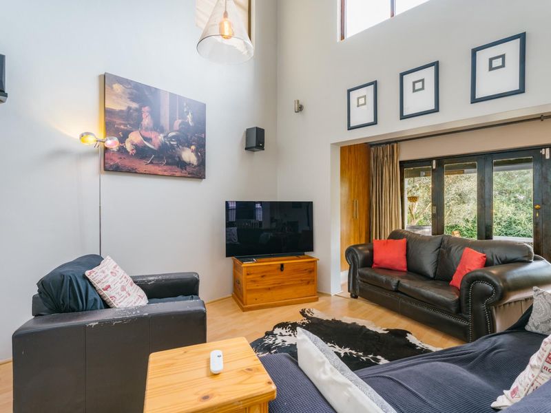 Spacious living room featuring double volume ceilings, laminate flooring, and large bi-fold doors that provide seamless access to the outdoor area.