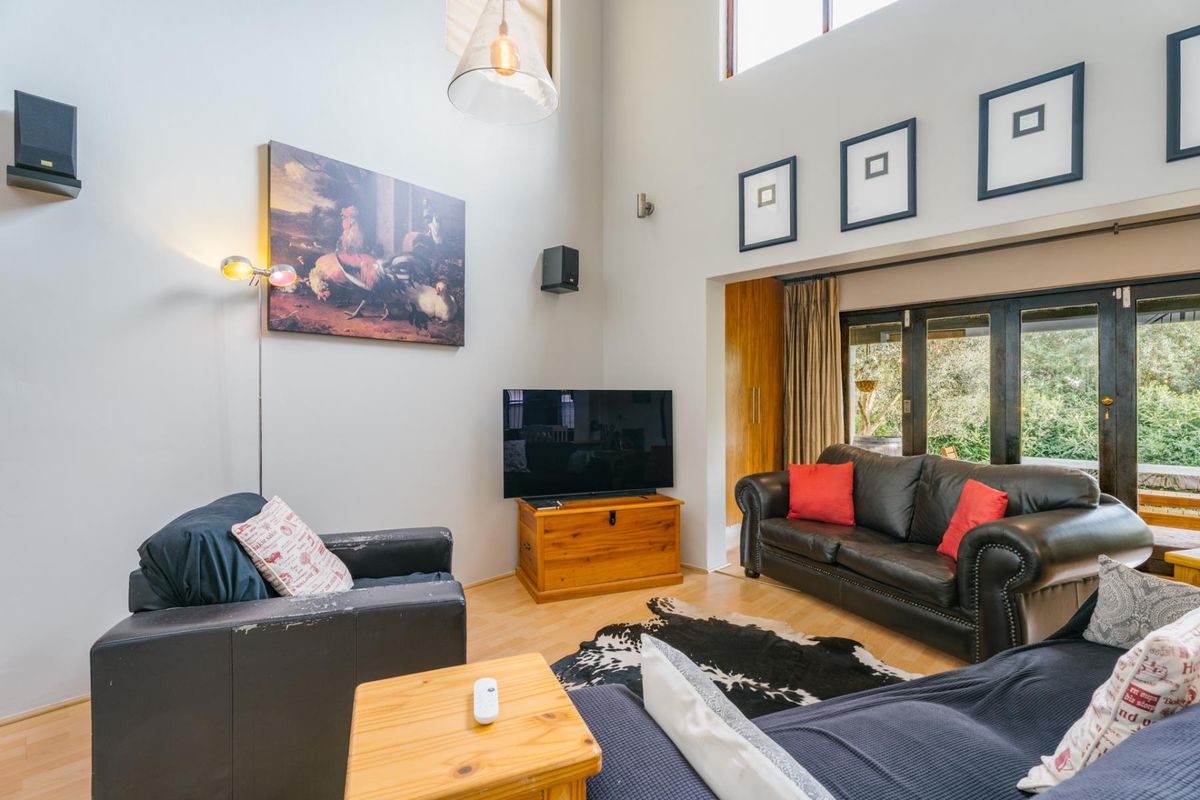 Spacious living room featuring double volume ceilings, laminate flooring, and large bi-fold doors that provide seamless access to the outdoor area.
