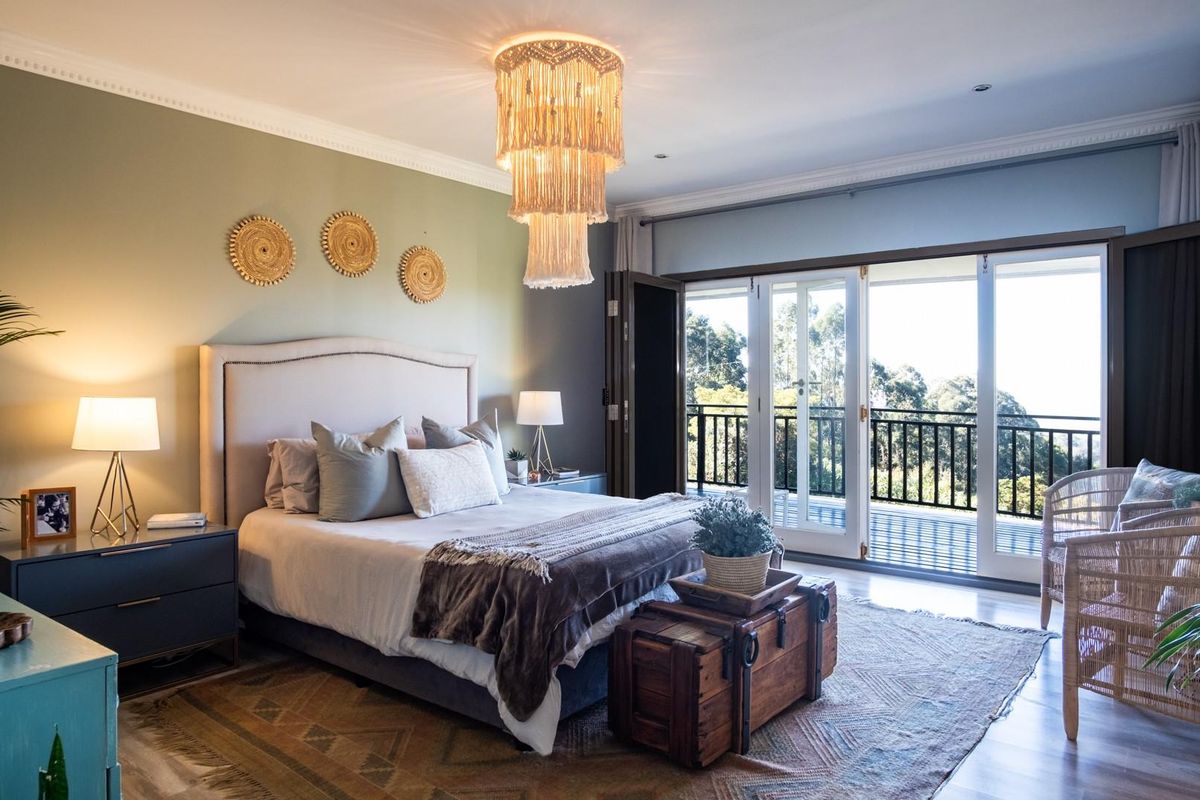 Spacious bedroom featuring elegant crown molding, recessed lighting, and large glass doors opening onto a private balcony with scenic views.