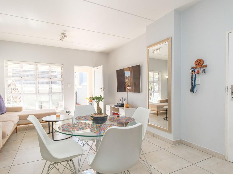 A bright and airy open-plan living and dining area featuring neutral tiled flooring and large windows that provide ample natural light.